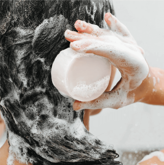 Applying solid shampoo bar for all hair types, ideal for dry and damaged hair, creating rich lather.